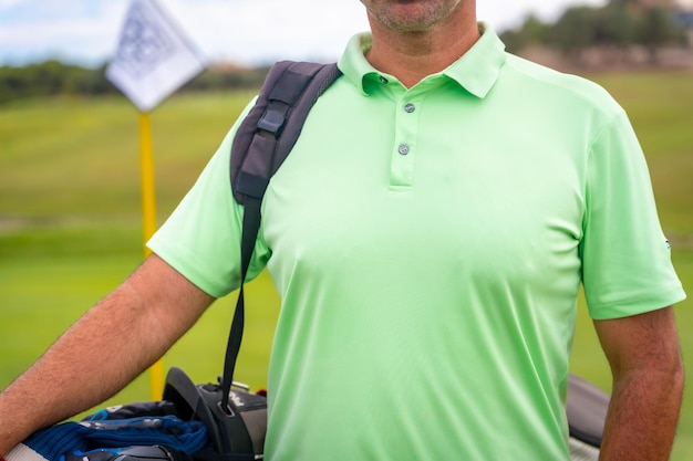 A male golfer walking down the fairway carrying bags