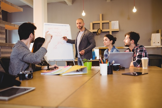 Male graphic designer discussing chart on white board with coworkers