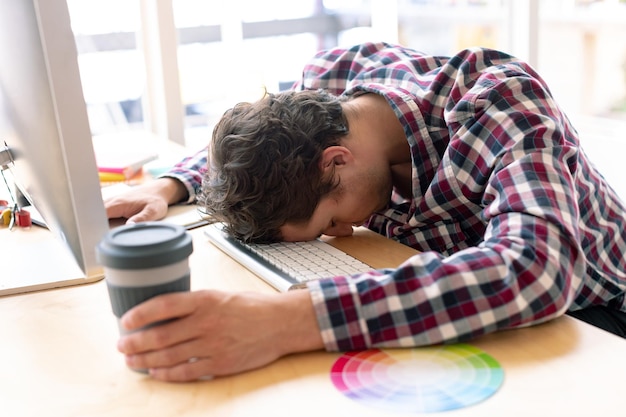 사진 현대적인 사무실에서 책상 위에서 잠을 자는 남성 그래픽 디자이너