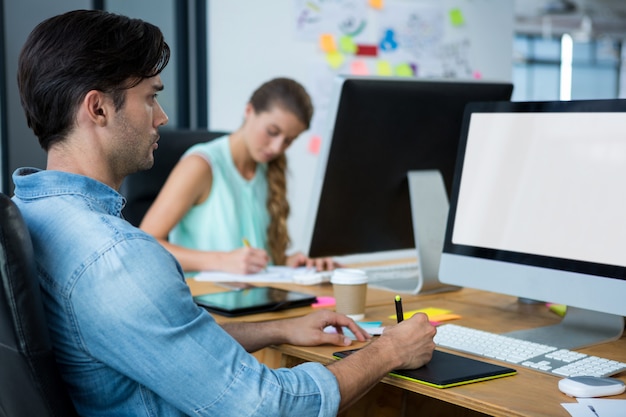 Male graphic designer using graphics tablet at desk