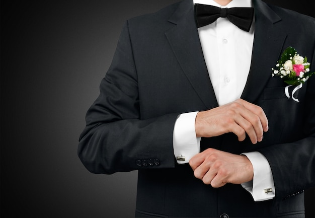 Male groom in wedding suit with bow tie on black