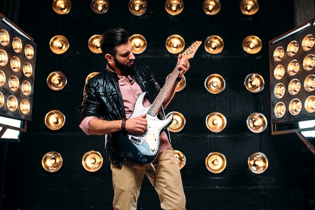 Фото Мужской гитарист на сцене с украшениями огней