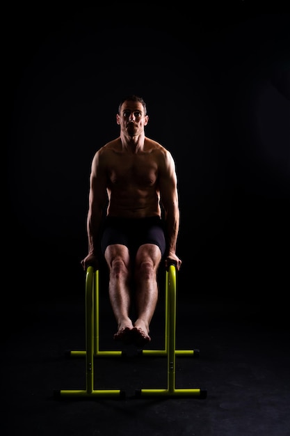 Male gymnast performing handstand on parallel bars studio shot