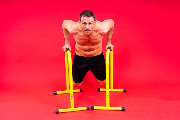 Male gymnast performing handstand on parallel bars studio shot