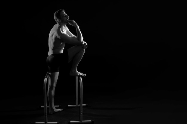 Male gymnast performing handstand on parallel bars studio shot