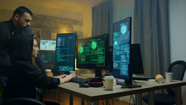 사이버 범죄자 소녀가 덮개 서버에서 데이터를 훔치는 방법을 보고 있는 남성 해커.