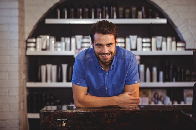 Male hairdresser leaning on table at a salon