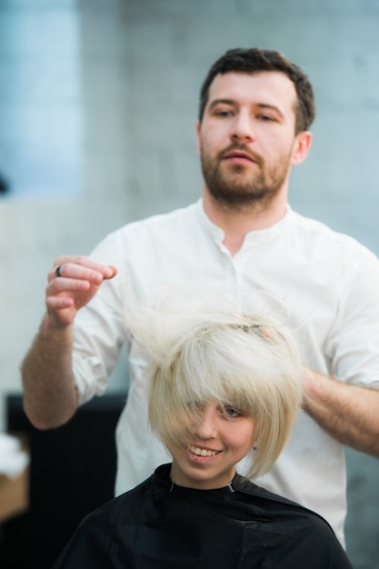 Foto il parrucchiere maschio mette i capelli della donna in un parrucchiere