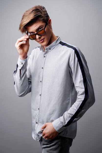 Концепция мужской прически красивый парень со стильной стрижкой в солнцезащитных очках на белом фоне