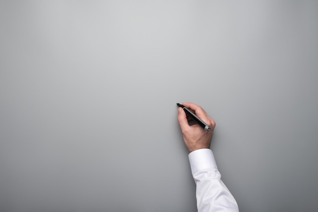 Male hand about to write on grey background