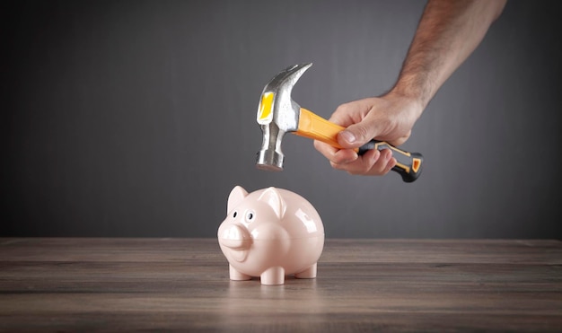 Male hand breaking piggy bank with hammer.