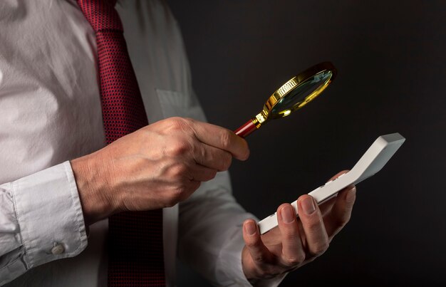 Male hand of businessman holding calculator and magnifier.