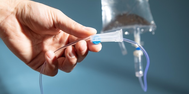 Male hand checking an intravenous drip on the blue background