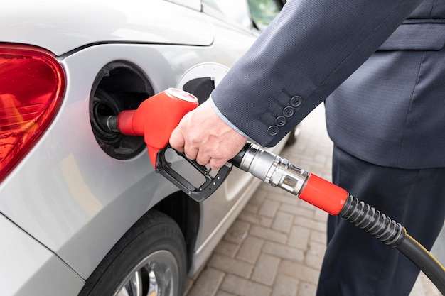 Male hand closeup refueling grey car higher oil prices