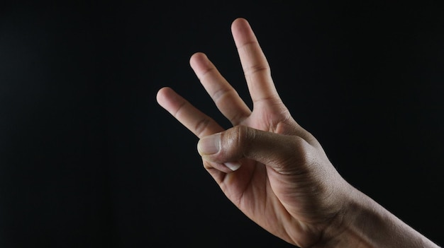 Photo male hand gesture number three closeup isolated on a black background