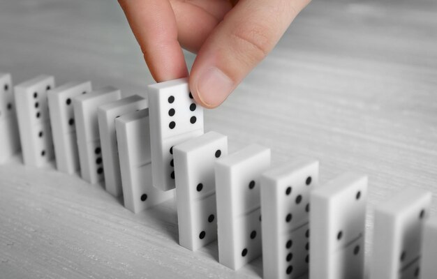 Male hand getting out domino from row on wooden table