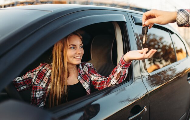 男性の手が女性のドライバーに車のキーを与える