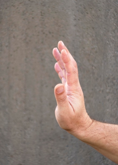 Male hand on a gray monophonic background in a welcome or negative gesture