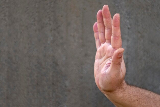 Male hand on a gray monophonic background in a welcome or negative gesture