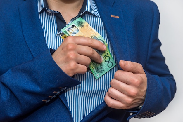 Male hand hiding australian dollar banknotes into pocket