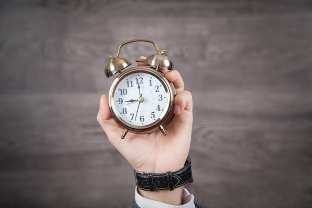 Male hand holding alarm clock.