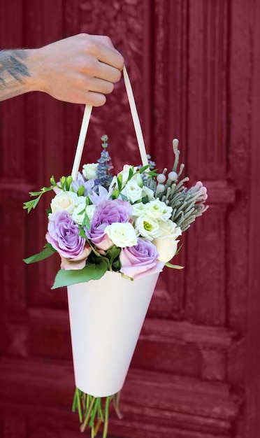 Male hand holding beautiful bouquet on door background