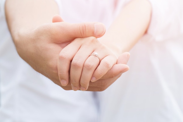 Male hand holding beautiful female hand with ring