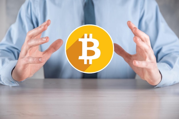 Male hand holding a bitcoin icon on grey background. Bitcoin Cryptocurrency Digital Bit Coin BTC Currency Technology Business Internet Concept.