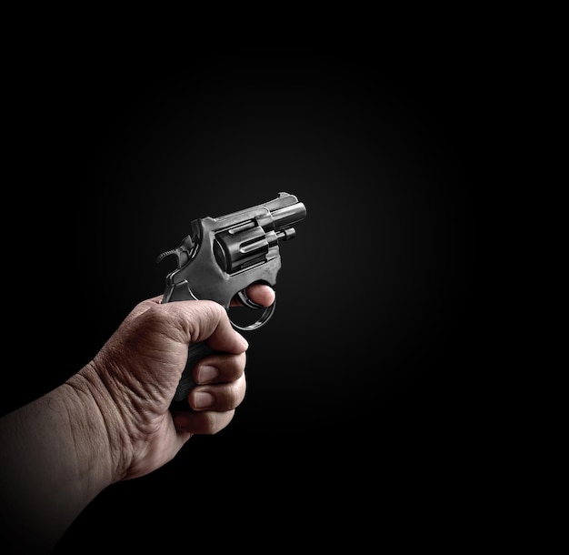 male hand holding a black revolver on a black background criminals with handguns at close range weapons for attack or defense