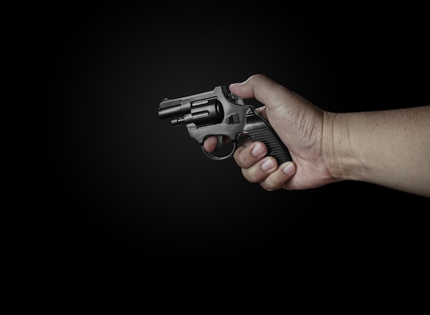 male hand holding a black revolver on a black background criminals with handguns at close range weapons for attack or defense