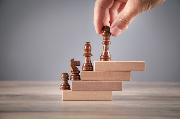 Male hand holding chess piece on wooden blocks.