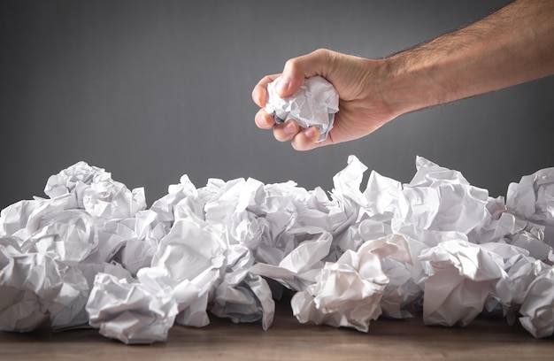 Male hand holding crumpled paper ball.