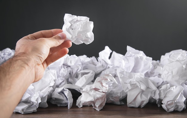 Male hand holding crumpled paper ball.