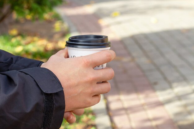 Photo male hand holding a disposable cup of coffee
