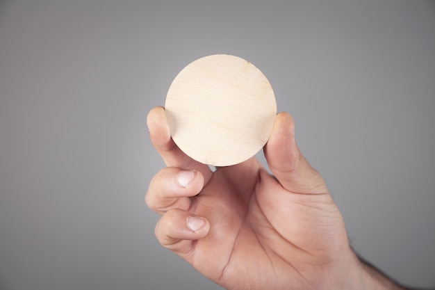 Male hand holding empty wooden round.