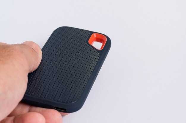 Male hand holding an external SSD Drive isolated on white background. Selective focus.