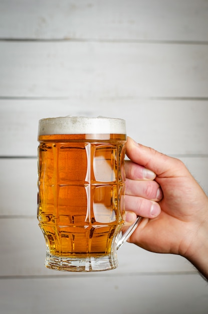male hand holding a full beer mug