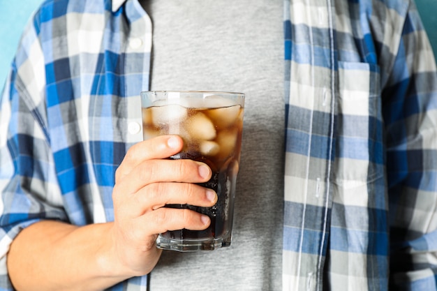 Male hand holding a glass with cola, close up