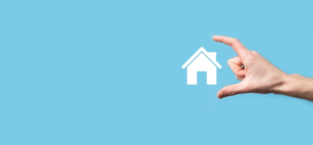 Male hand holding house icon on blue background. Property insurance and security concept.Real estate concept.