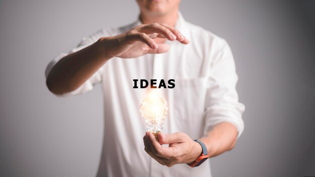 Фото Мужчина с освещенной лампочкой в руке новая идея инновация и вдохновение концепция и идеи слово