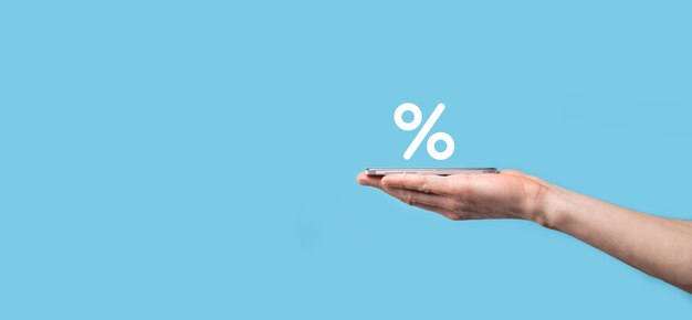 Icona di percentuale del tasso di interesse della holding della mano maschio sulla superficie blu