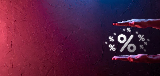 Фото Мужская рука держит значок процента процентной ставки на синем фоне концепция процентных ставок и ипотечных ставокбаннер с копировальным пространством