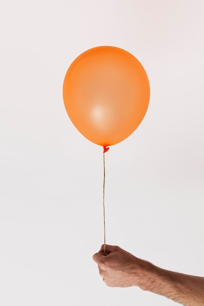 Male hand holding an orange celebration balloon