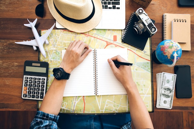 Male hand holding pen on notebook over map. Planning a trip,copy space. Travel background