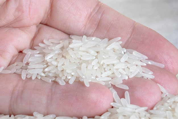 마른 흰 쌀 더미를 들고 있는 남성 손 유기농 자연 식품 건강 관리