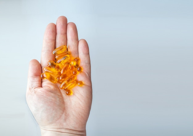 Male hand holding pills on gray background