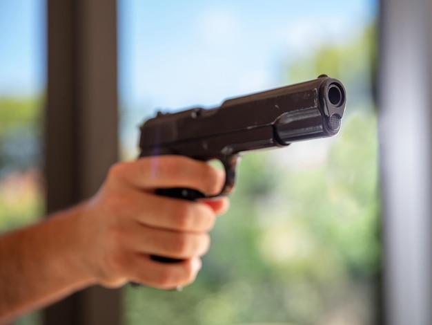 Male hand holding a pistol blur nature background