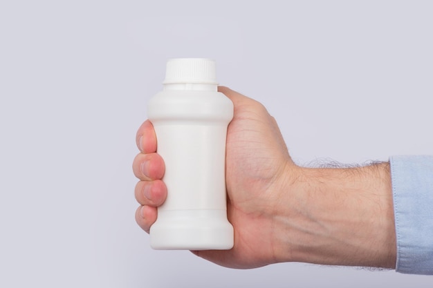 Male hand holding plastic bottle of pills Close up Copy space Template Mockup