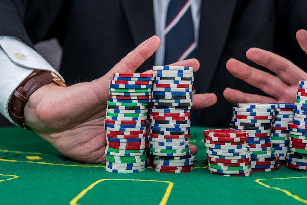 Male hand holding poker chips in casino green felt Gambling concept