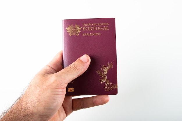 Mano maschio che tiene passaporto portoghese su sfondo bianco